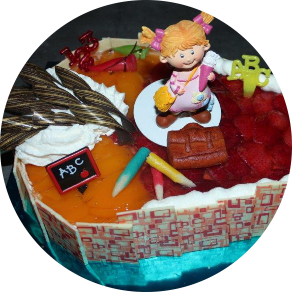 Ein Fruchtherz mit Schulanfangsdeko auf der Torte und weißer Schokoladentafeln ringsum. Der Link auf dem Bild führt zur Produktübersicht unserer Schulanfangstorten.